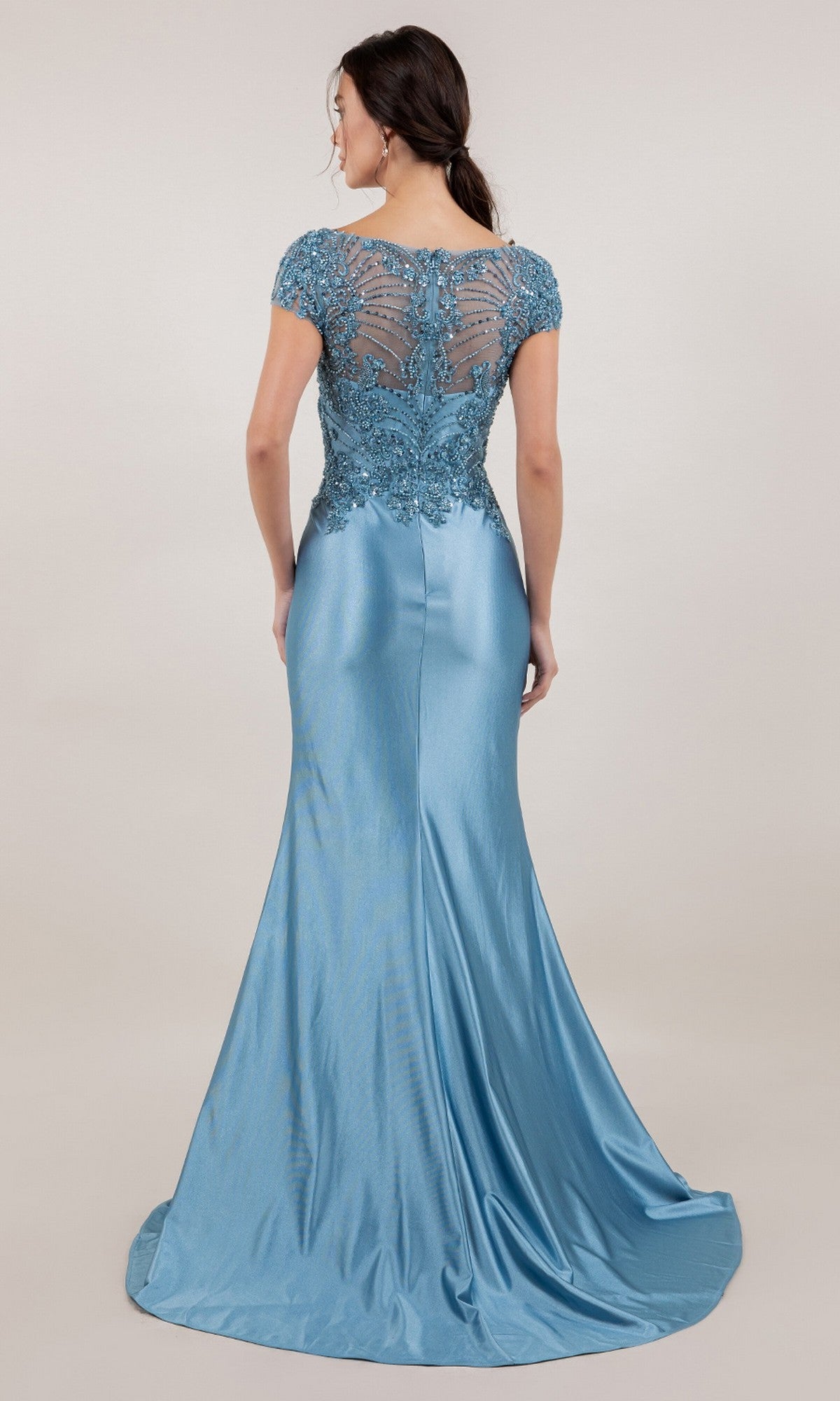 A woman stands with her back to the camera in a fitted, floor-length light blue Cinderella Couture 8513M gown featuring lace detailing, a v-neckline, and sheer back against a plain background.